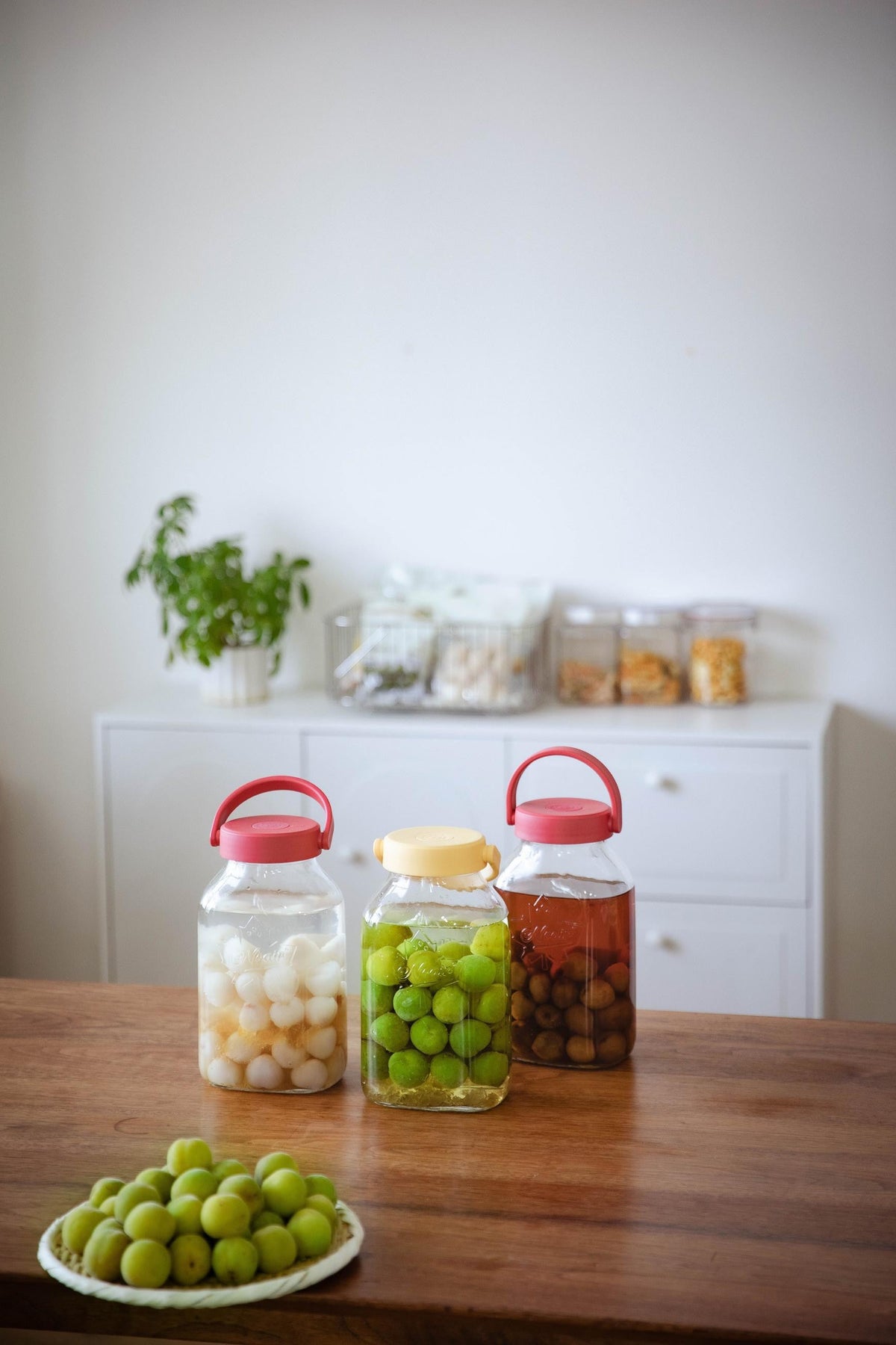 Glass preserving jars with fruit on a wooden kitchen bench